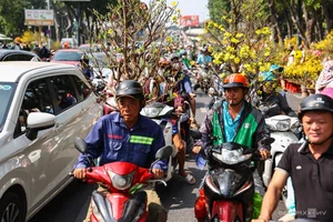 Bustling Scenes: Crowds Rush for Discounted Tet Flowers in Ho Chi Minh City - image 11